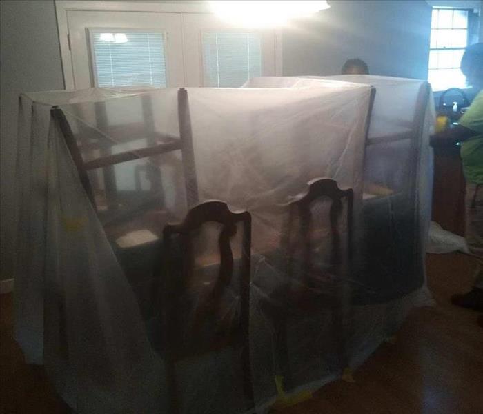 picture of wood dining table with chairs stacked on top and wrapped in plastic